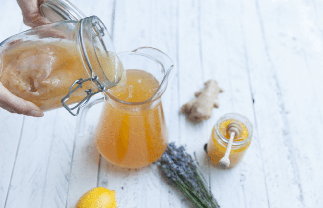 A woman purs homemade Kombucha into a pitcher